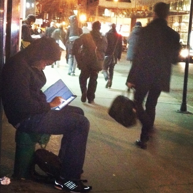 Guy sitting on sidewalk with iPad