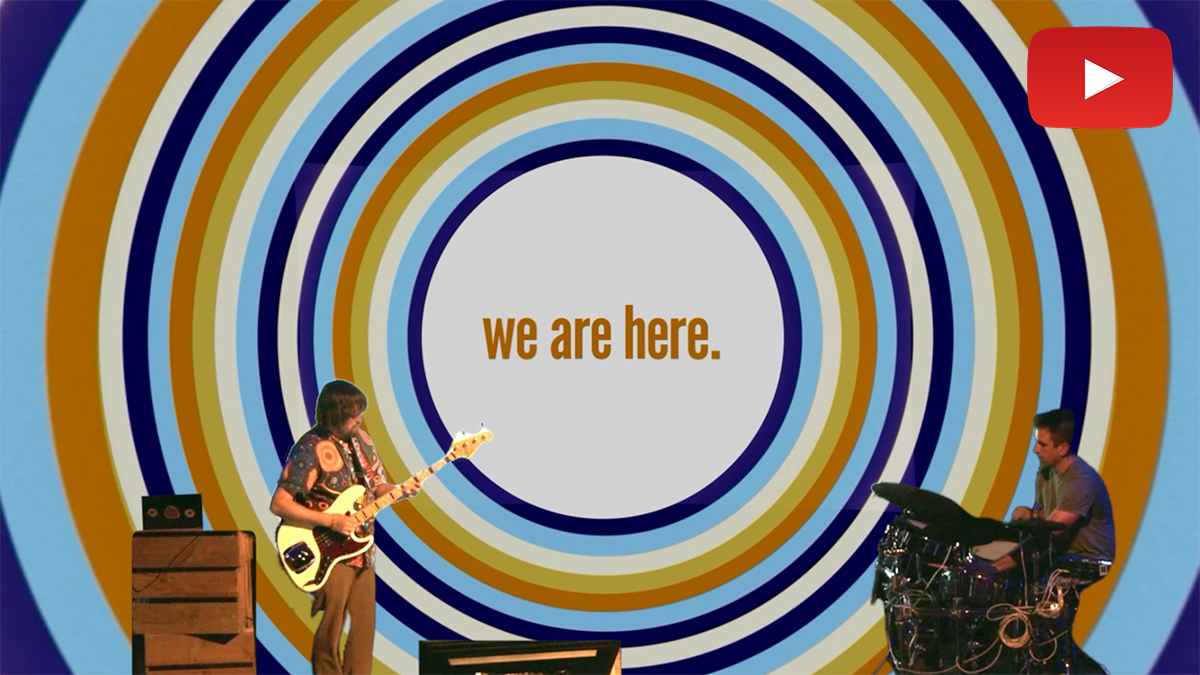 Video still of Brad and Ian performing 'we are here.' on stage