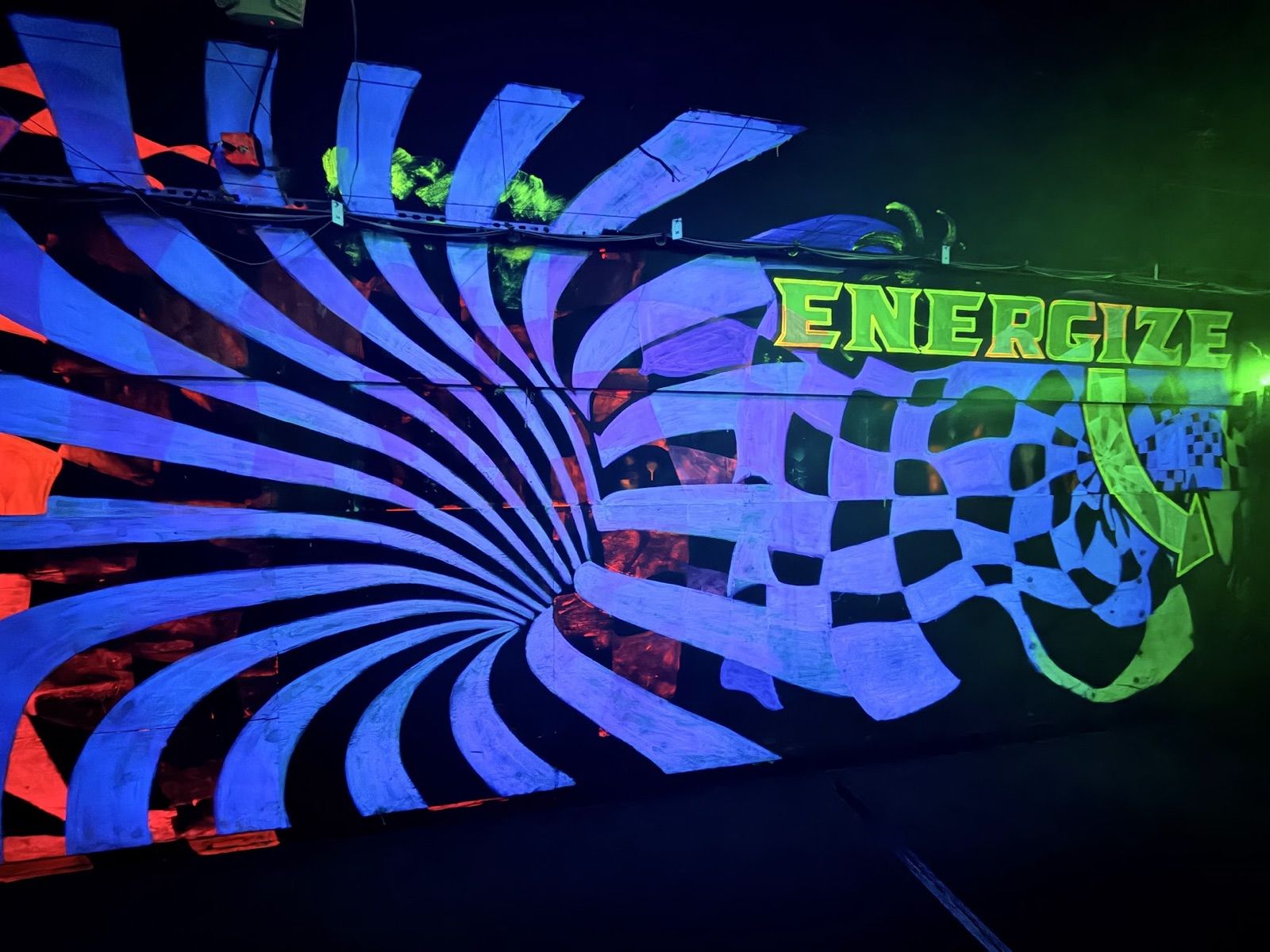 A blue-and-white vortex blending into a checkerboard under a glowing green "ENERGIZE" sign
