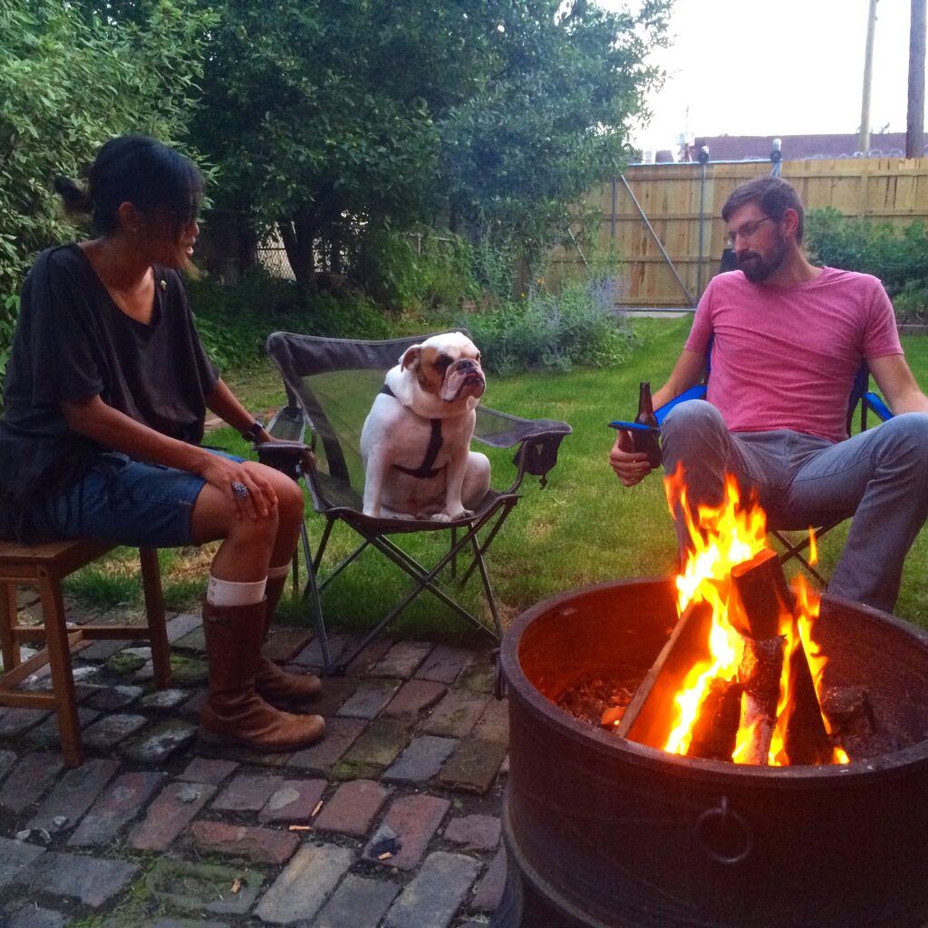 Ziggy sitting in a campchair with friends sitting around a fire