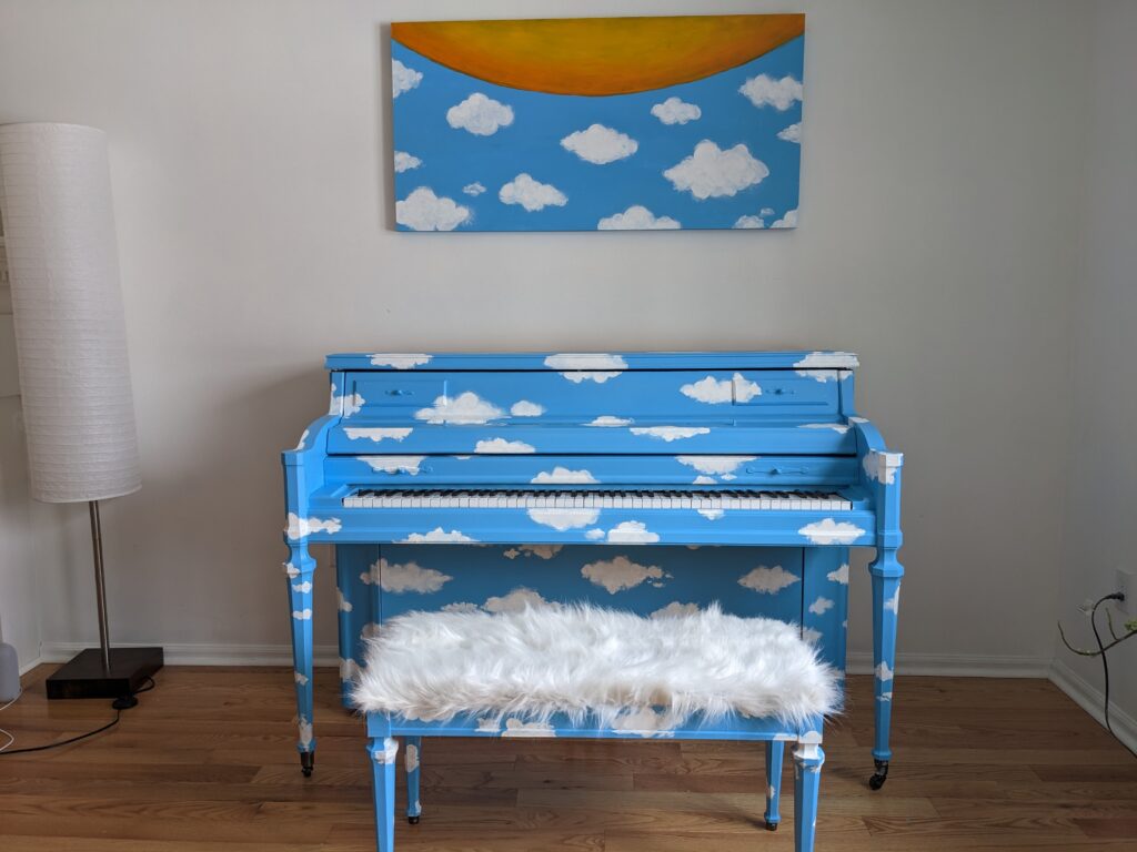 A piano painted sky blue with puffy white cloud pattern