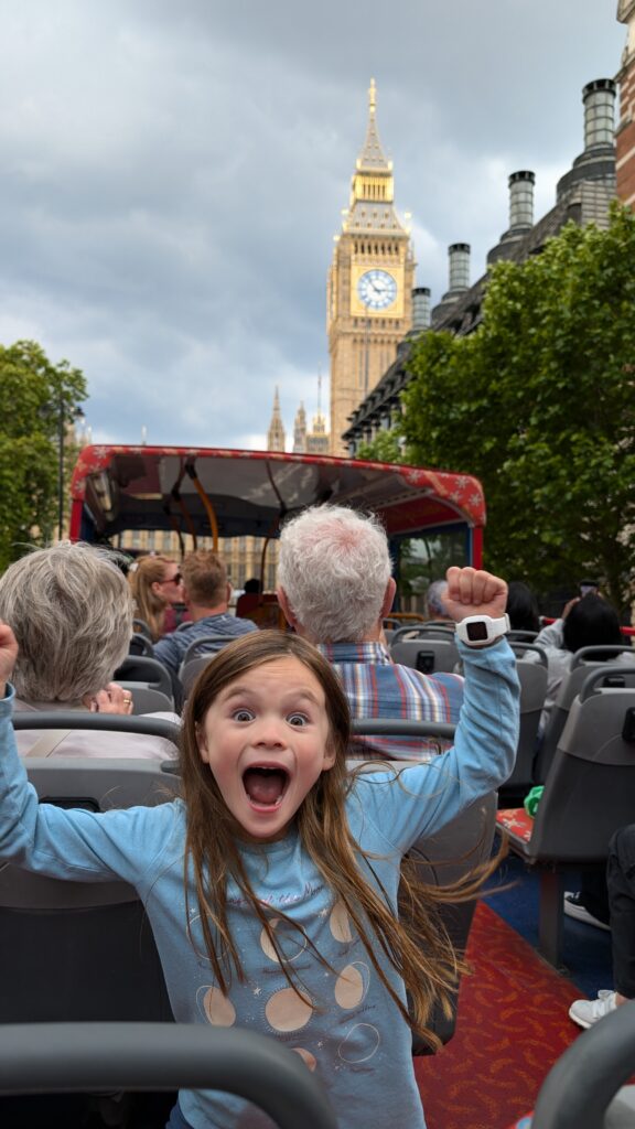 Ella excitedly posing on a double-decker bus in front of Big Ben