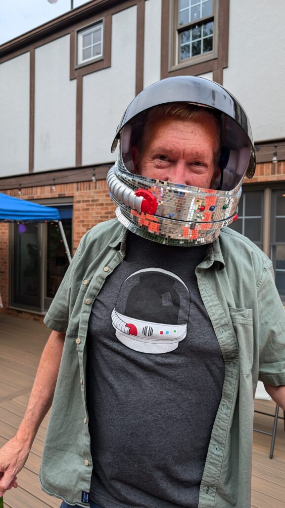 Scott Jenson wearing a disco ball helmet and a tshirt that features an illustration of the same helmet