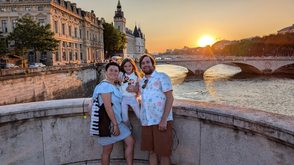 Brad and family posing for a picture in front of a Parisian sunset