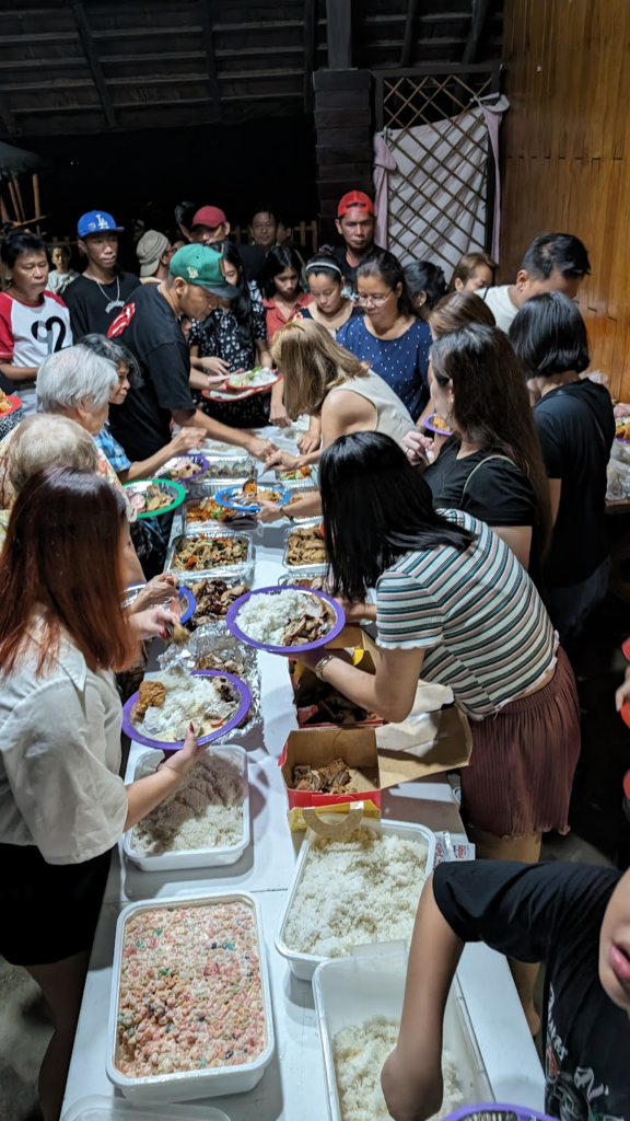 A buffet spread of delicious Filipino food with people digging into it